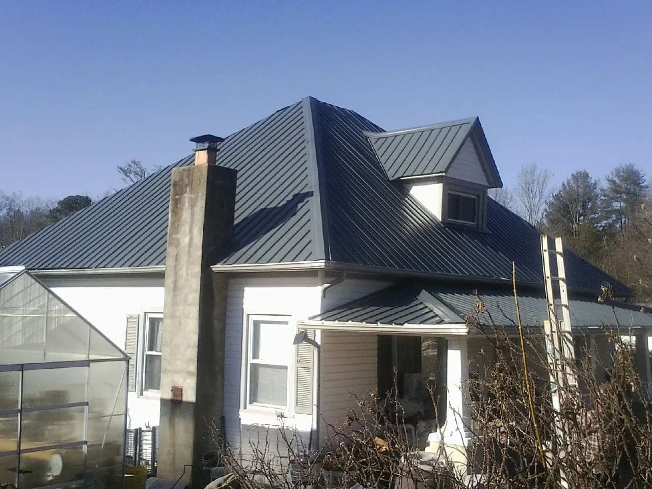 Dark blue standing seam metal roof on a white farmhouse with dormer — Slate & Tile Roof Repair by Roofing Brothers in White Salmon