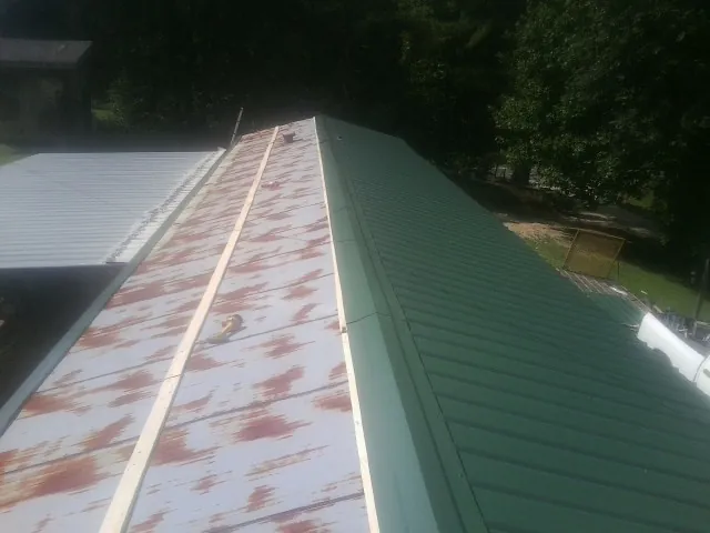 Old rusted panels beside newly installed green metal roofing — Wind Damage Roof Repair by Roofing Brothers in White Salmon