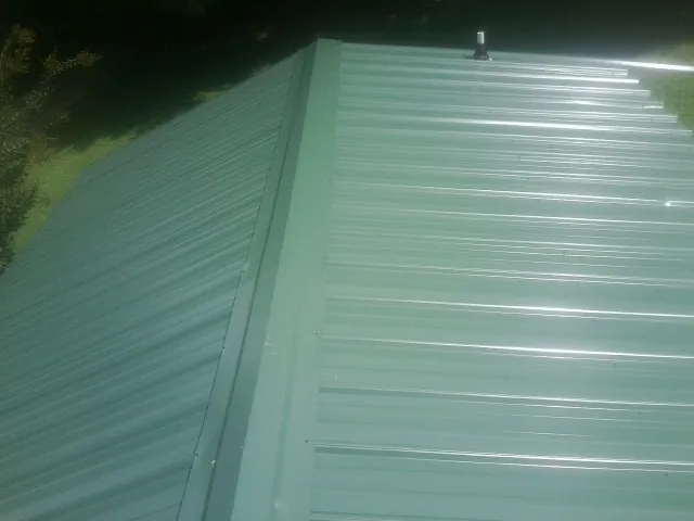 New green metal panels meeting at the ridge of a roof — Flat Roof Repair work by our crew in White Salmon