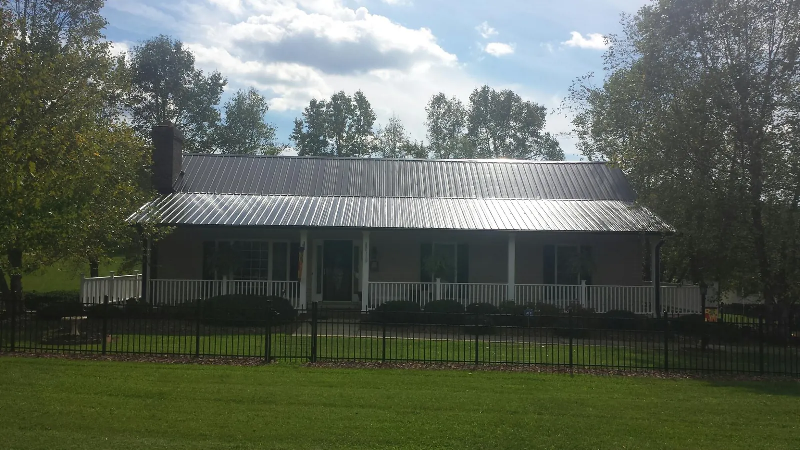 Gray metal roof on a brick ranch with a full width front porch — Gutter Guard Installation work by our crew in White Salmon