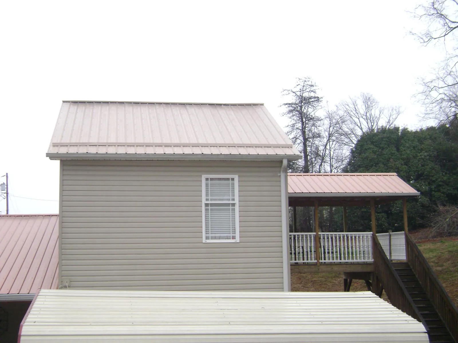 Tan metal roofs on a two story addition and attached porch, from a Roof Replacement job in White Salmon