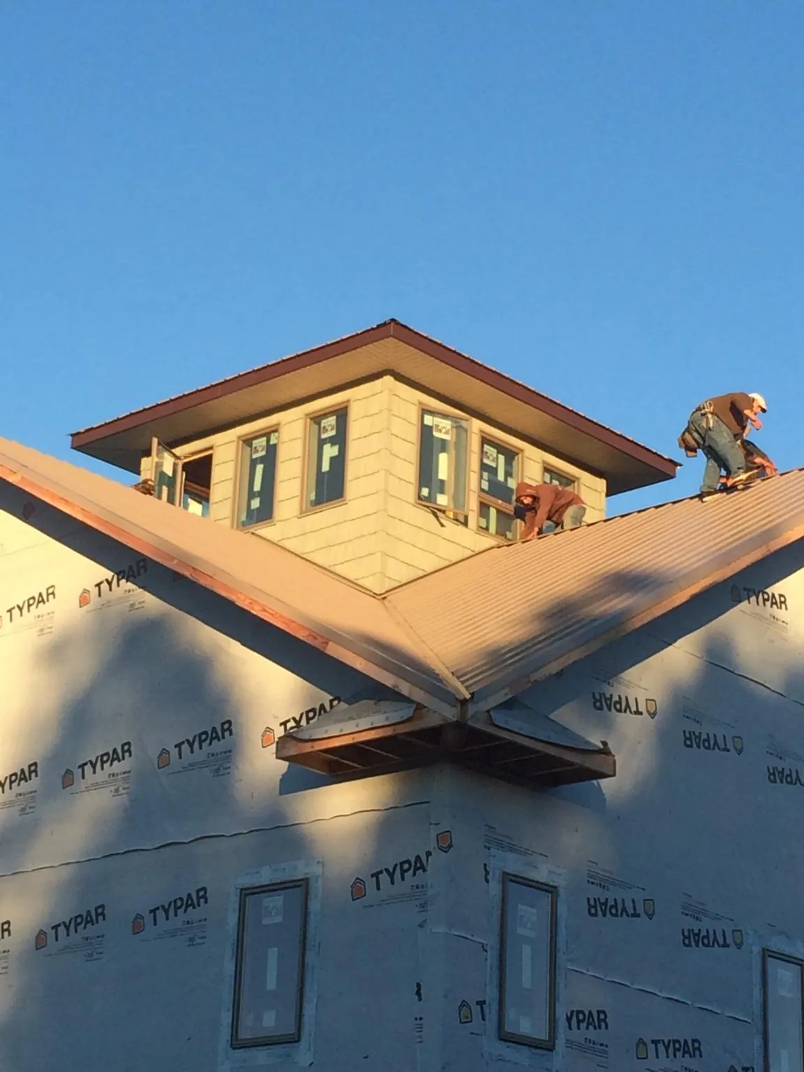 Roofers working around a rooftop cupola on a new metal roof at sunset — Roof Waterproofing in White Salmon by Roofing Brothers